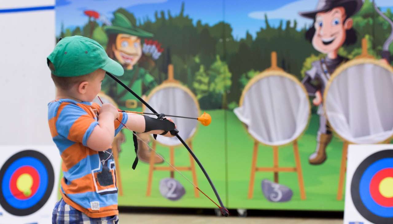 Young boy aiming a bow in Little Outlaws 