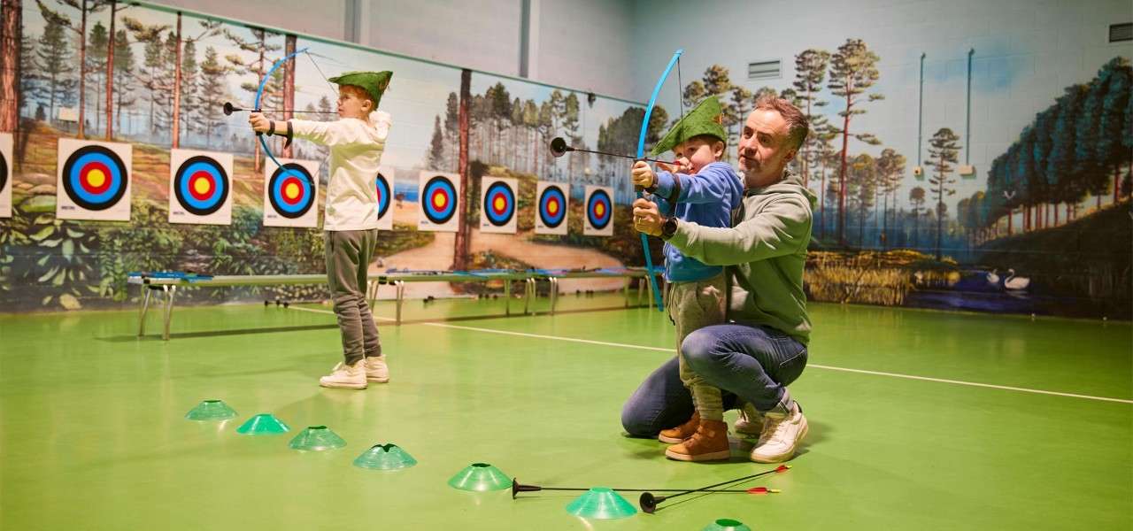 Father and son holding a bow and arrow ready to shoot at the target