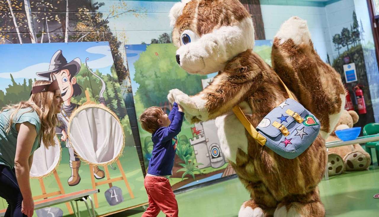 Young boy high fiving the Chestnut character. 