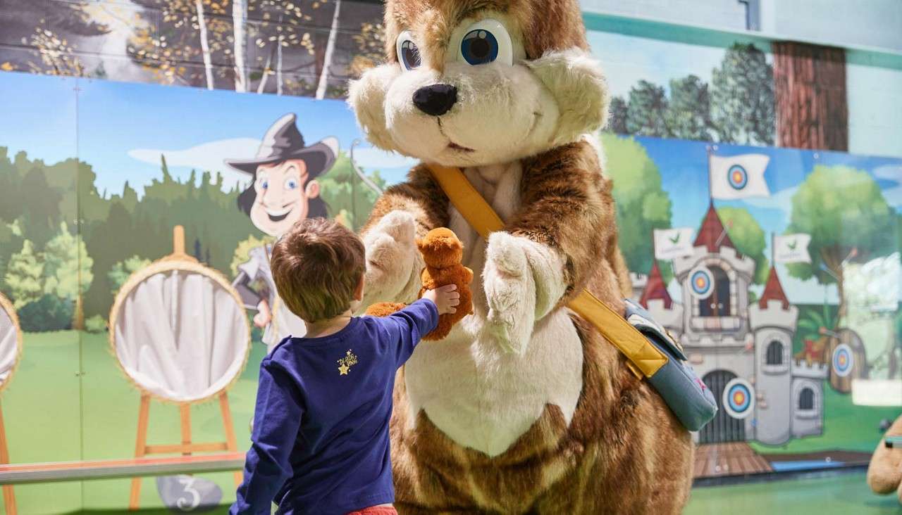 Young boy presenting a stuffed animal to the Chestnut character.