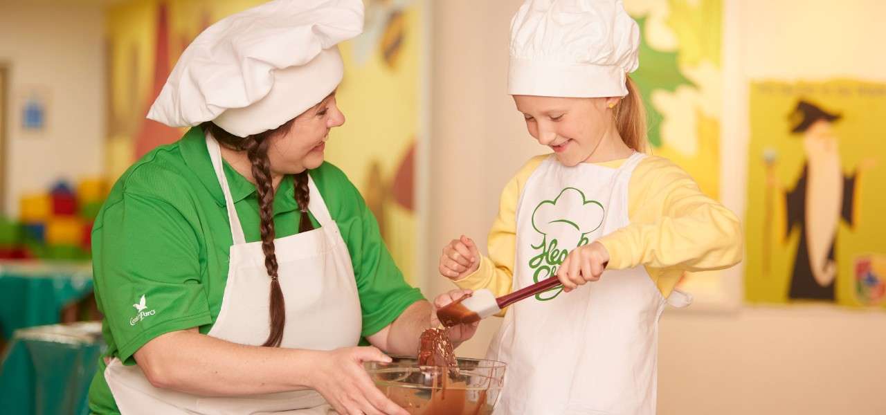 Woman and a young girl mixing a bowl filled with melted chocolate.
