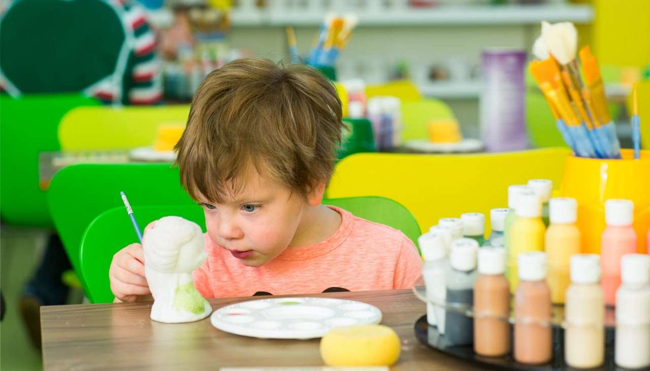 Young boy painting a piece of pottery.