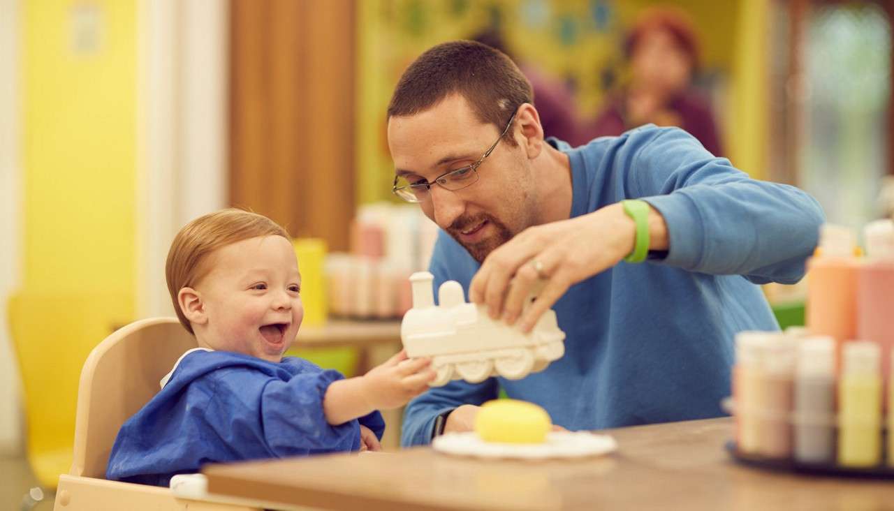 Young boy with his dad painting a train pot.