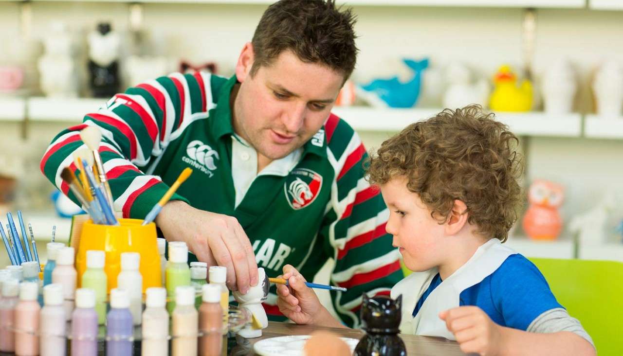 Young boy with his dad painting pots.