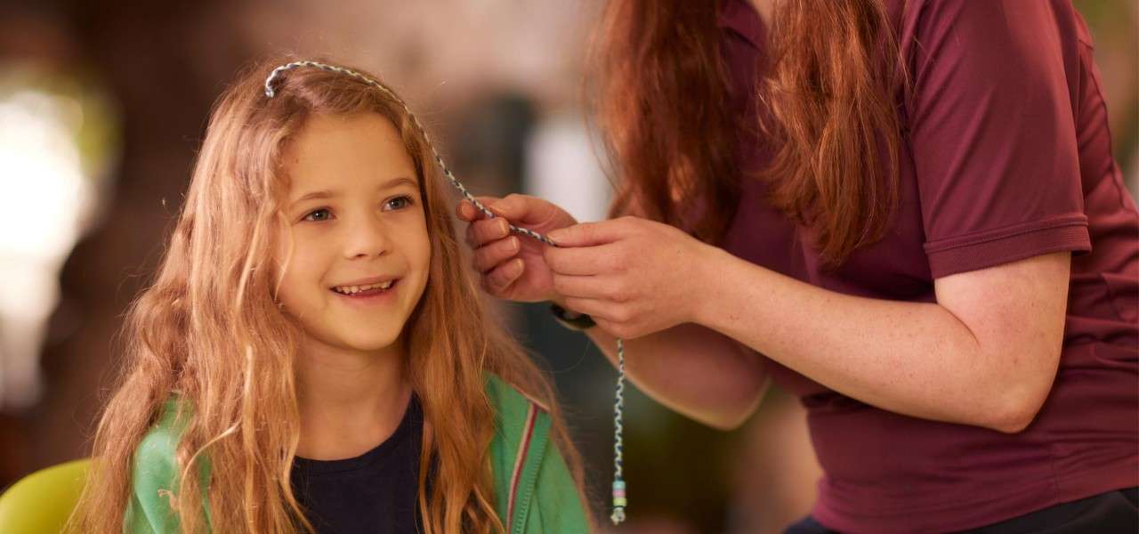 child having hair braided