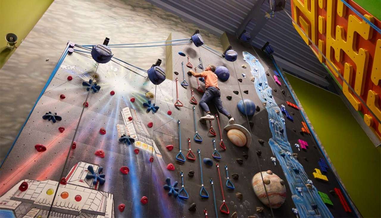 Man reaching the top of an indoor climbing wall