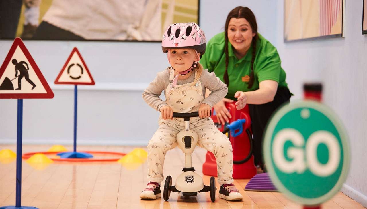 Young girl learning to use a scooter