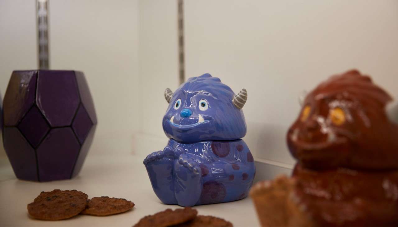 Ceramic monster pots lined up on a shelf.