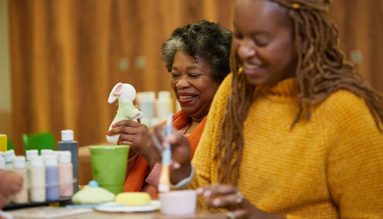 Two women painting ceramic pots.