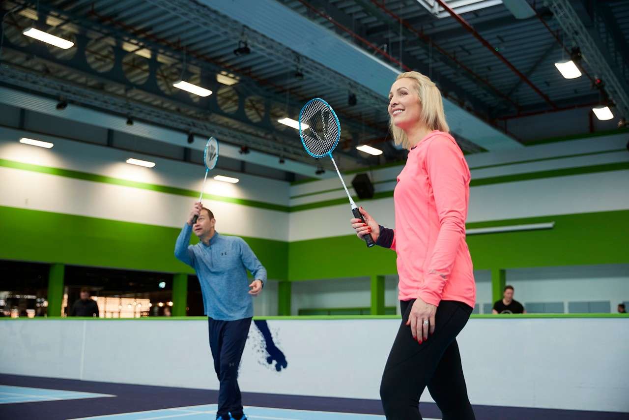 Two adults getting ready to play badminton