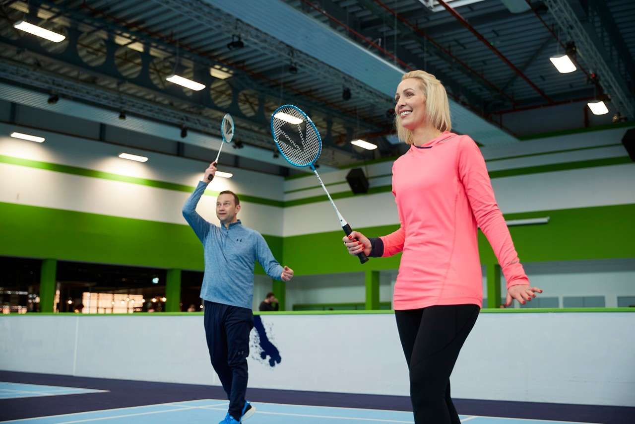 Two adults holding rackets in the air