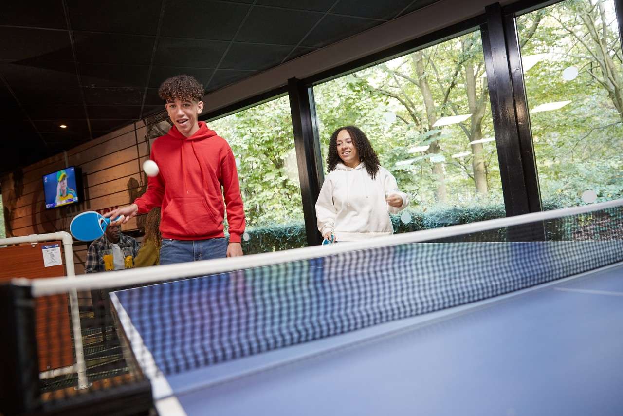Two teens playing doubles table tennis
