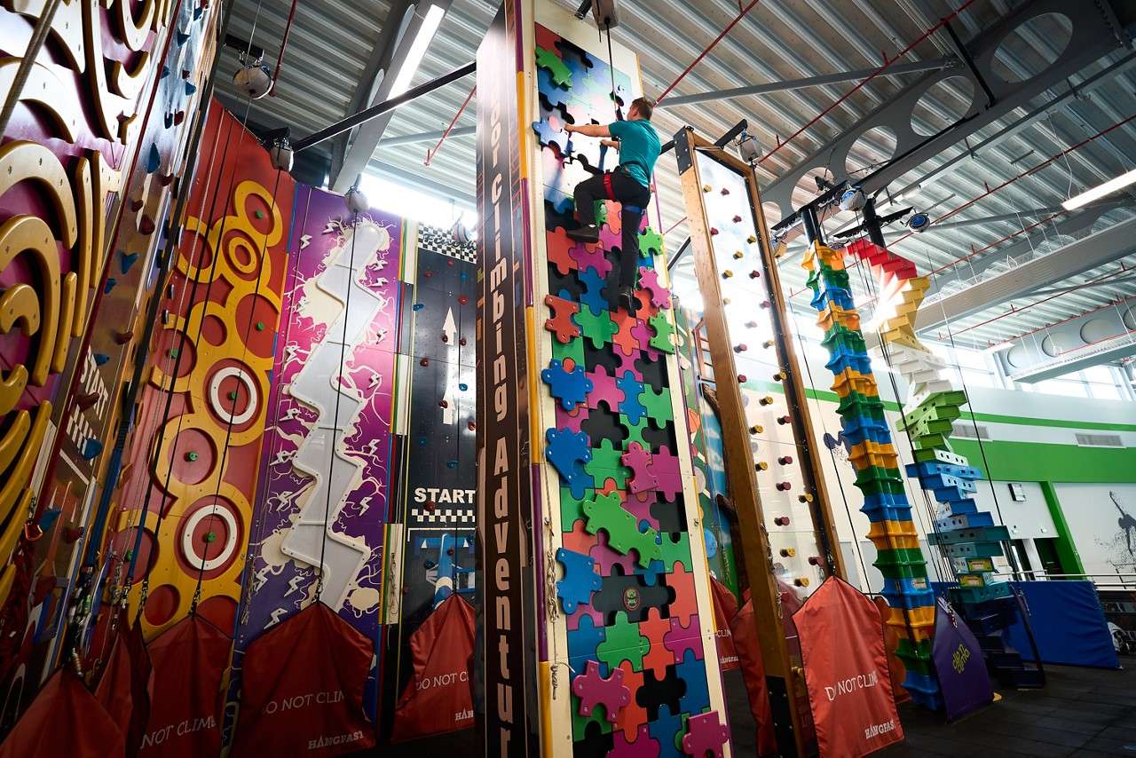 A shot showing the height of the climbing wall with someone climbing up to the top. 
