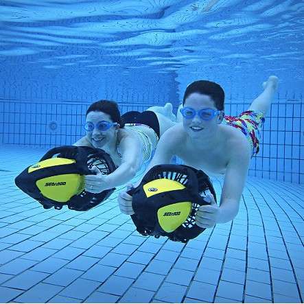 Two children smiling under water wearing goggles and aqua jetting.