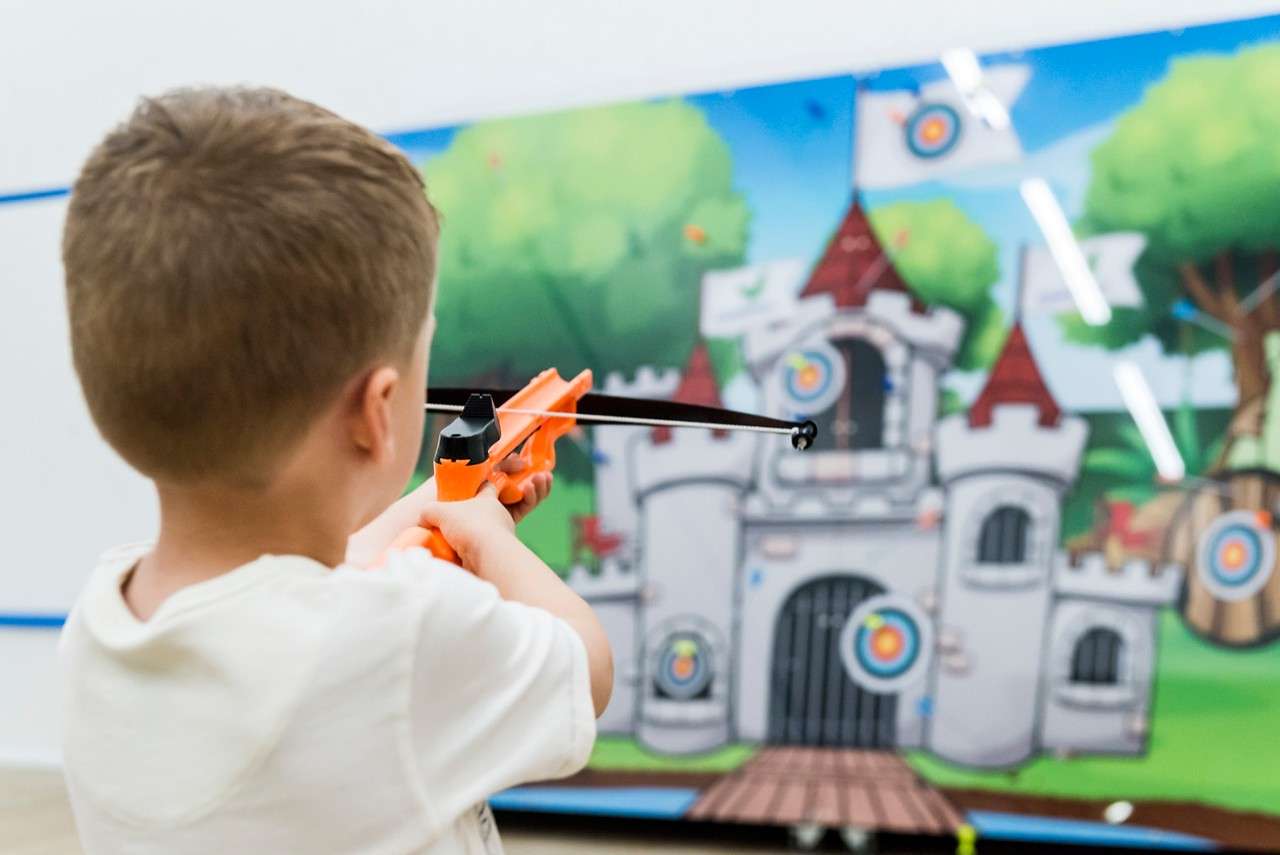A little boy aiming at targets on a castle.