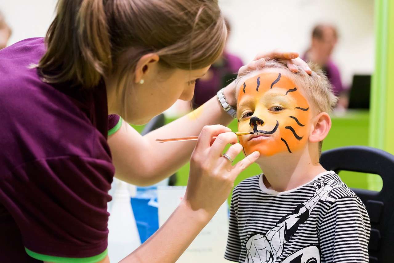 A little boy having his face painted as a tiger