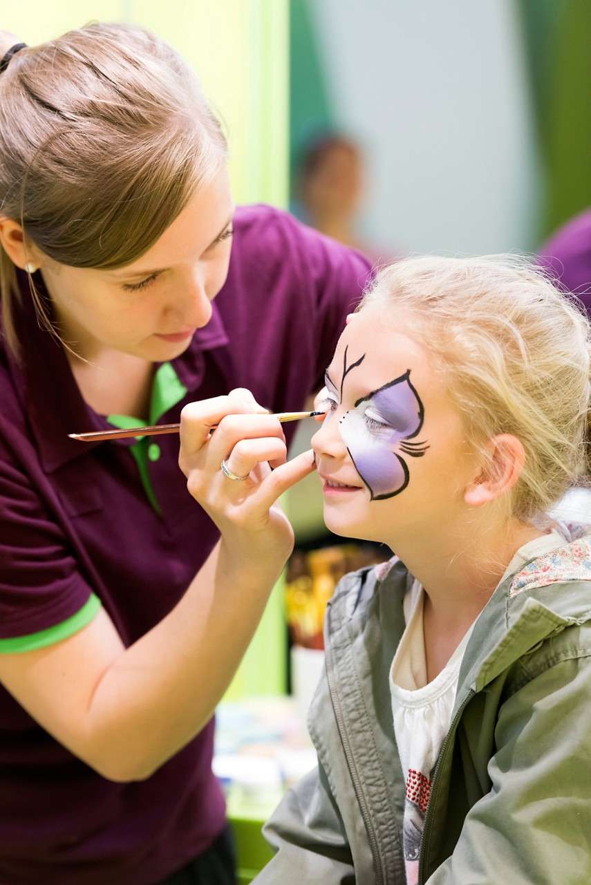 A little girl having a butterfly painted on her face