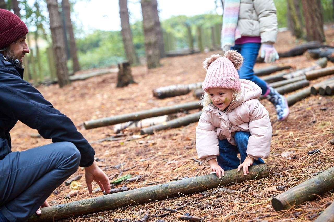 A little girl picking up a branch