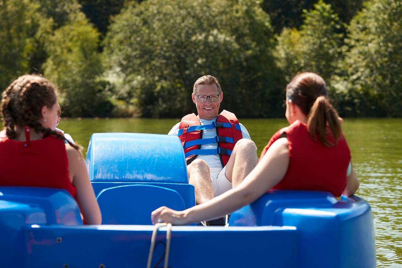 A family on a blue pedalo on a lake. 