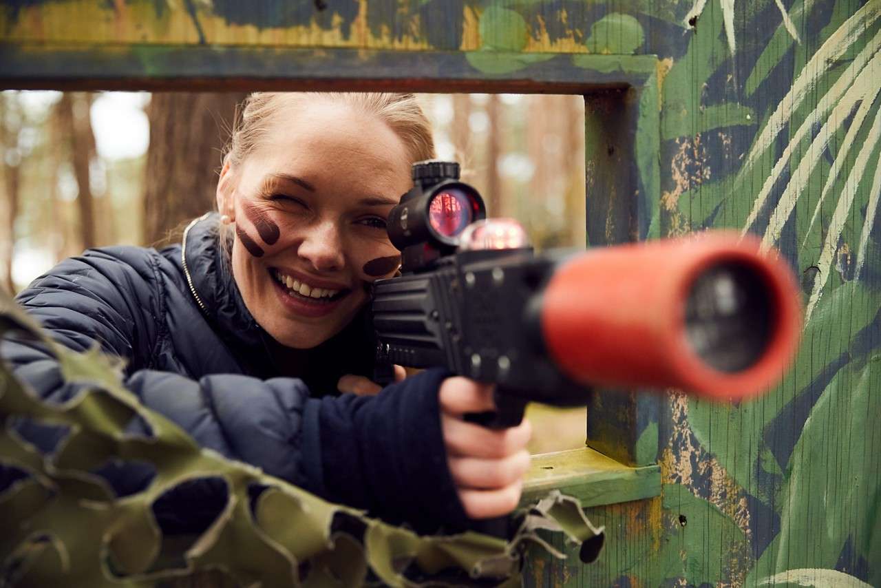 A girl smiles as she takes aim with a laser gun.