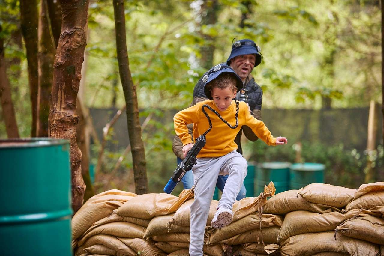 A young boy darting over a pile of sandbags.