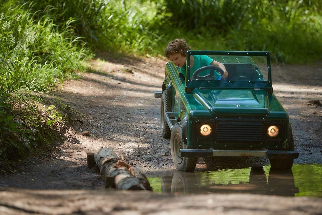 A little boy watching as he splashes through the puddle in the car. 