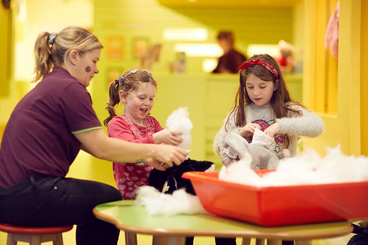 Two girls stuffing teddies at a table