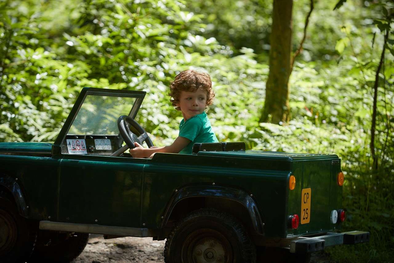 A child looking over his shoulders in the mini land rover 