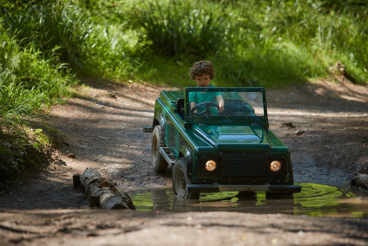 A boy driving through a puddle