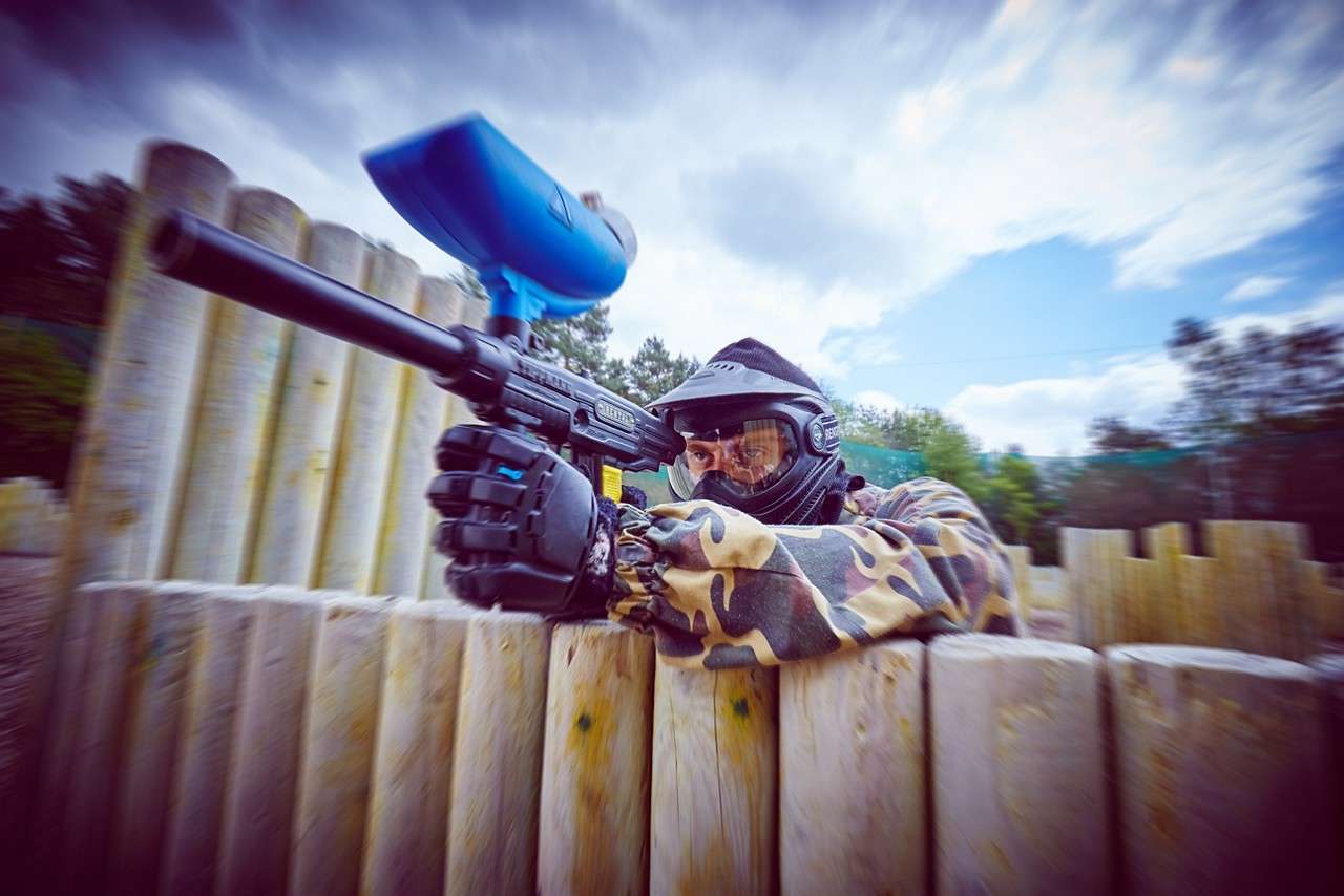 A person shielding behind a barrier with a paintball gun