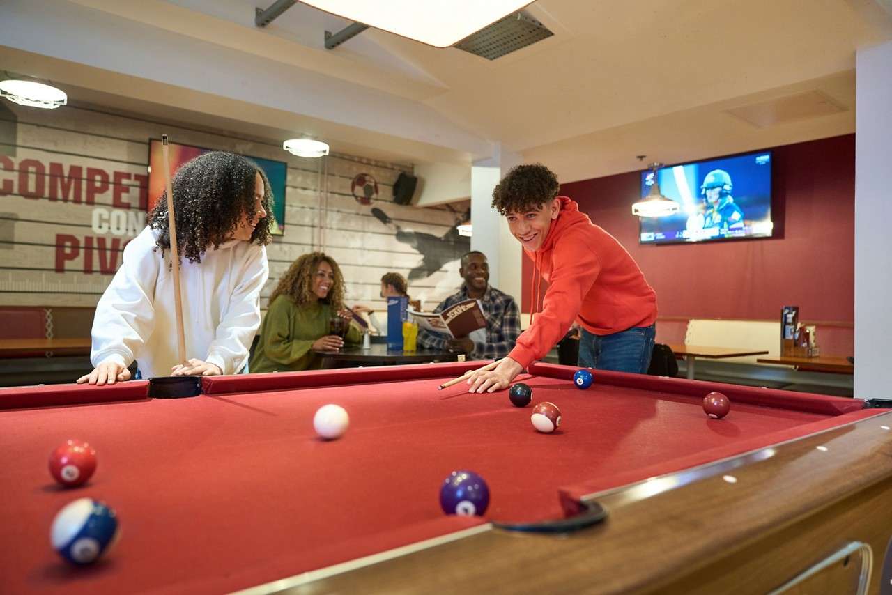 A boy aiming his pool cue