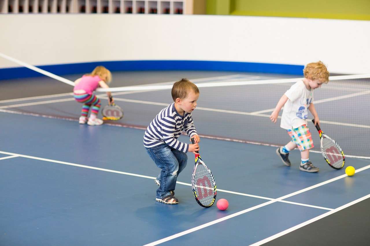 Little toddlers holding rackets for short tennis