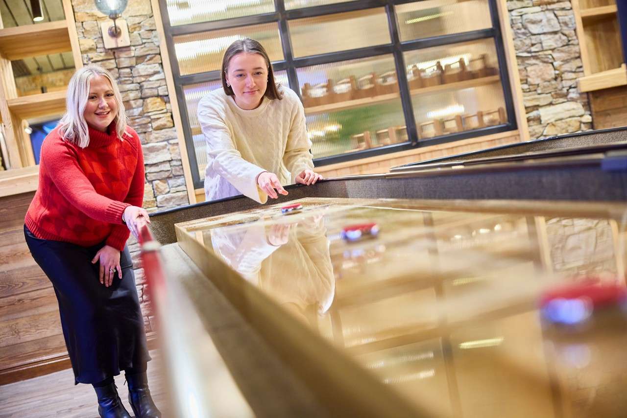 Two girls sliding puts down the shuffleboard 