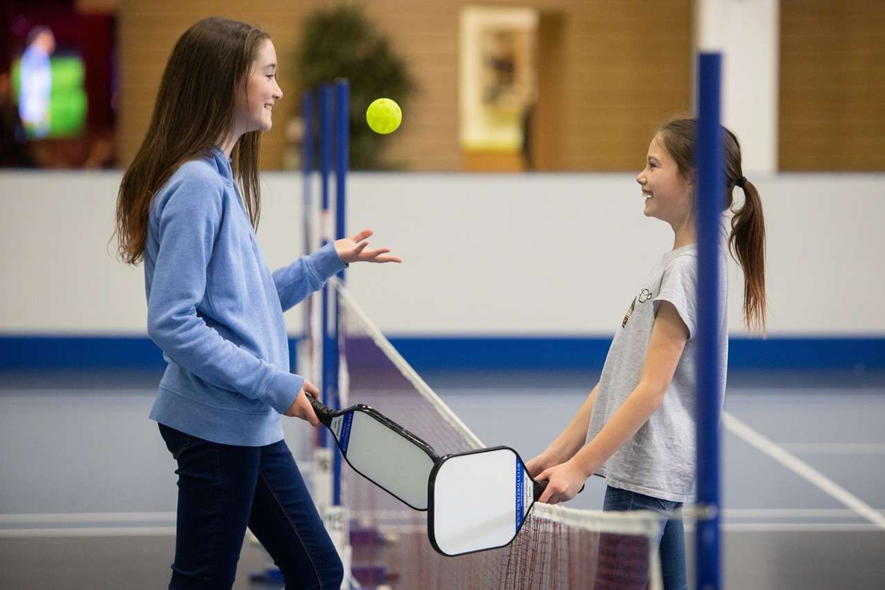 Two girls talking while playing pickleball