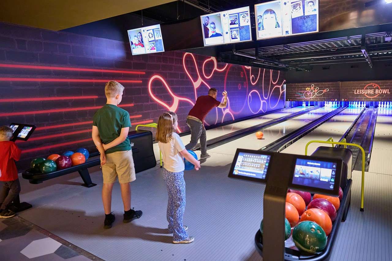 A family watching as someone looks for a strike in bowling 