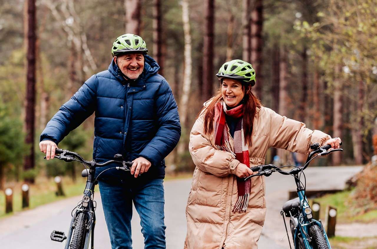Family riding their bikes through the forest.