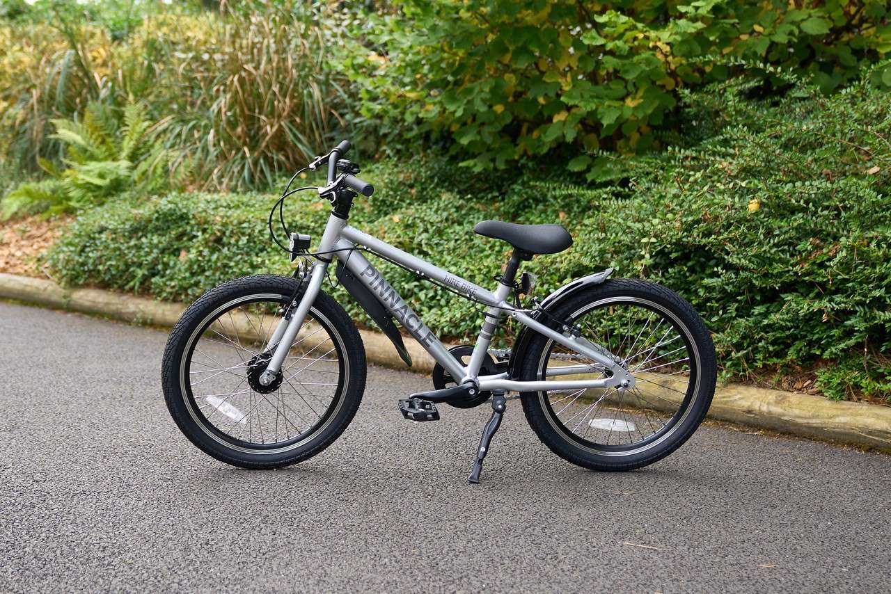 Bike rested on a wooden fence in the forest.