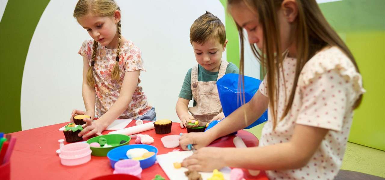 A group of young children decorating cupcakes.