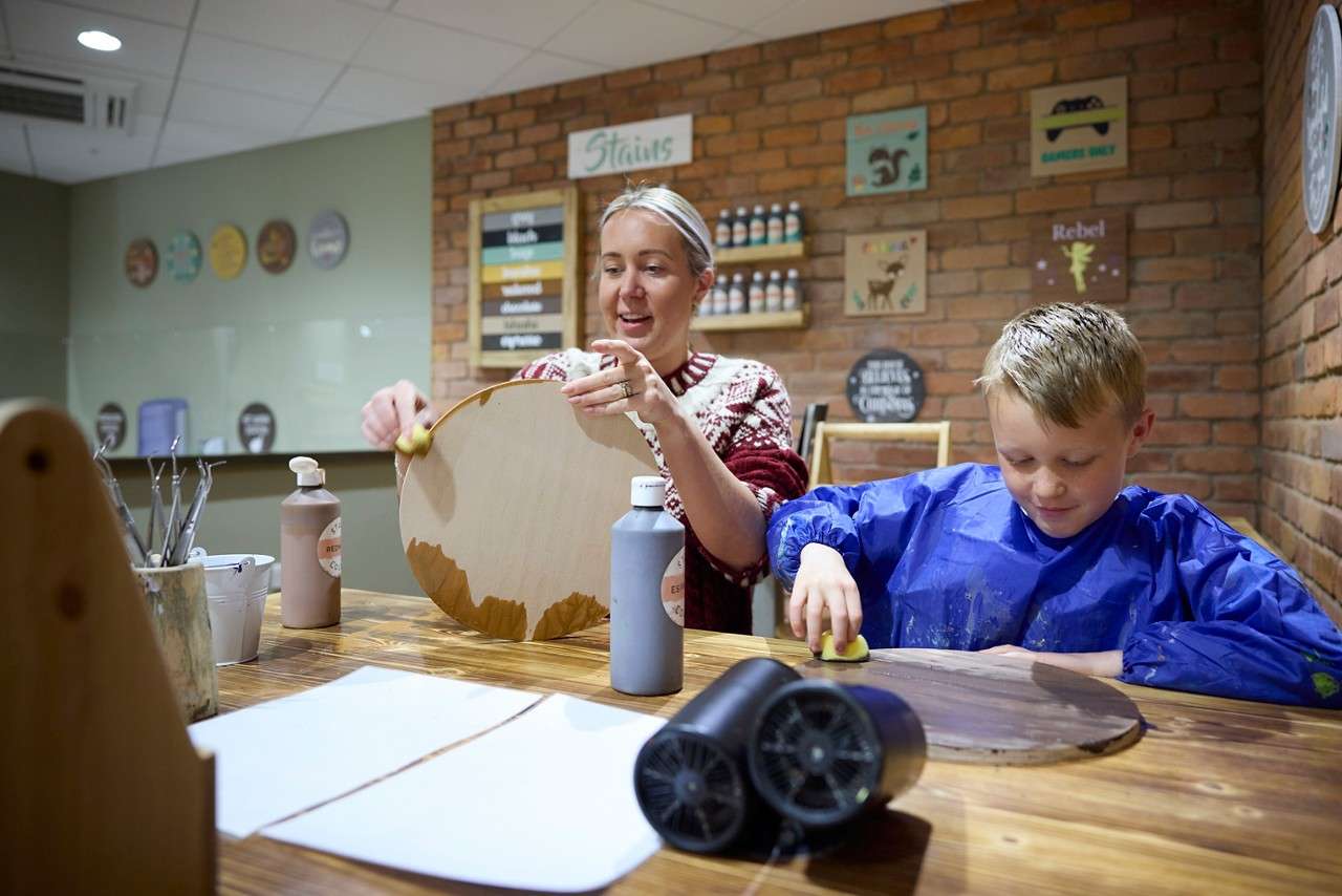 Two people sanding pieces of wood.