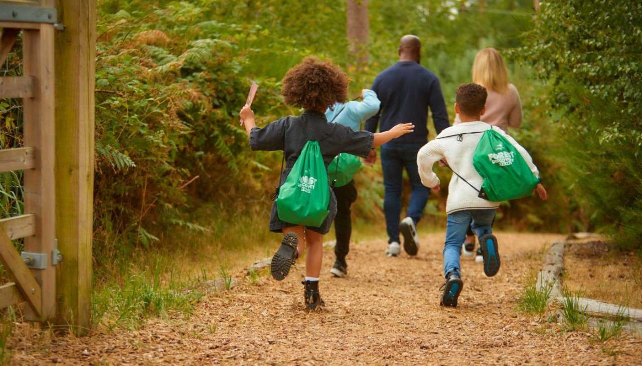 Family running along a woodland path.