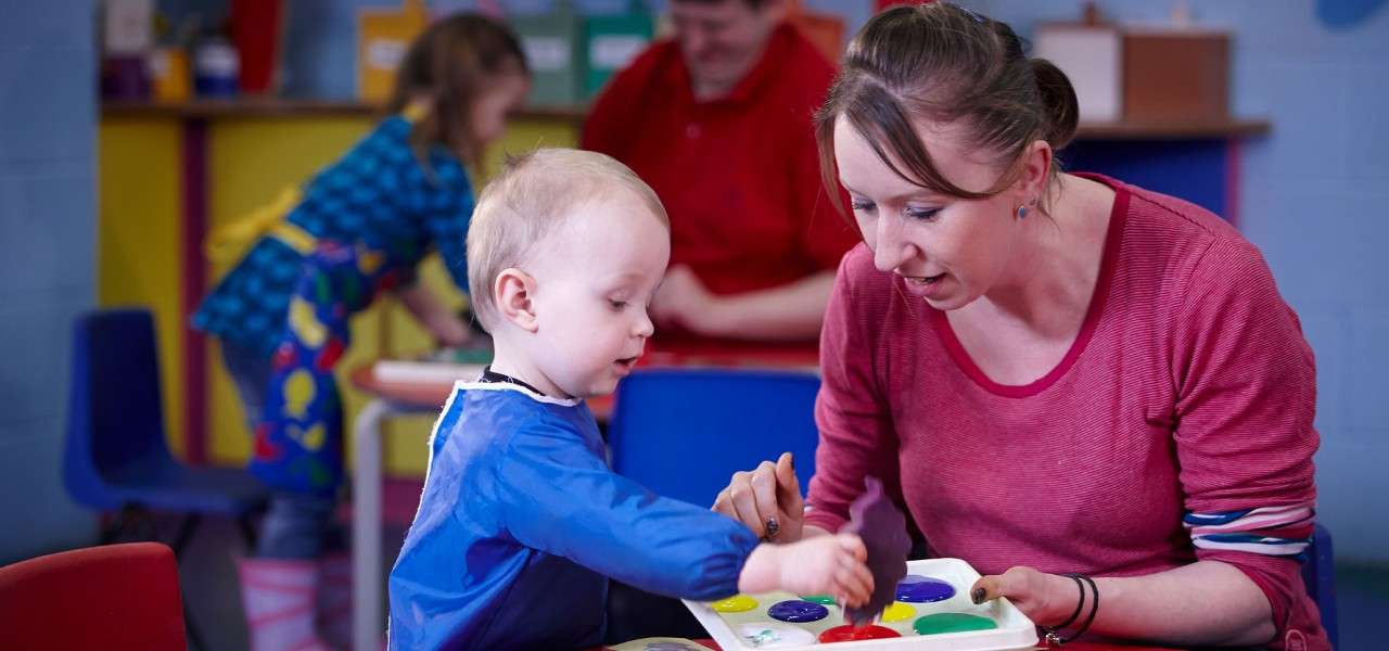 Young boy and a woman taking part in some messy play.