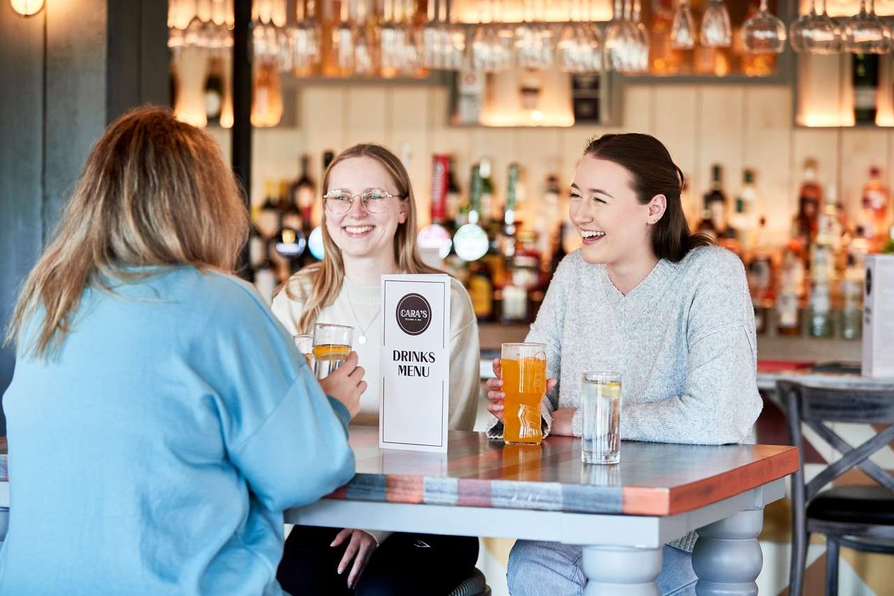 three adults enjoying a drink at cara's kitchen