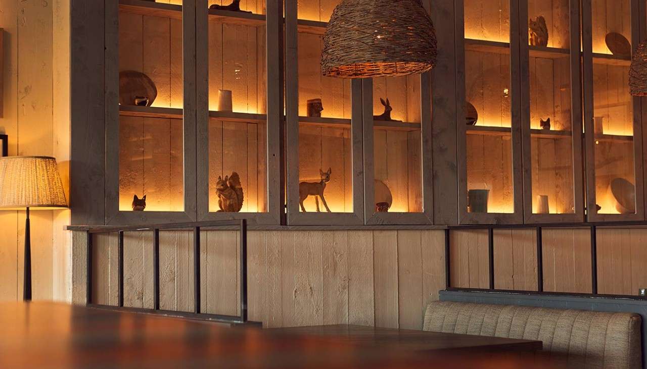 Details of the decor, showing wicker light shades, and wooden ornaments in a warmly-lit cabinet