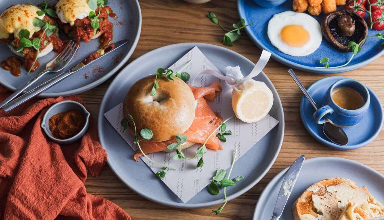 A selection of breakfast options including a salmon bagel and poached eggs.