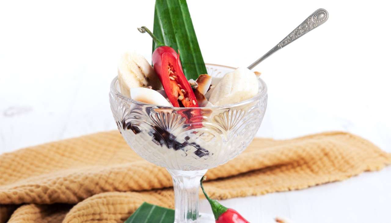 Dessert displayed in a glass topped with sliced chilli.
