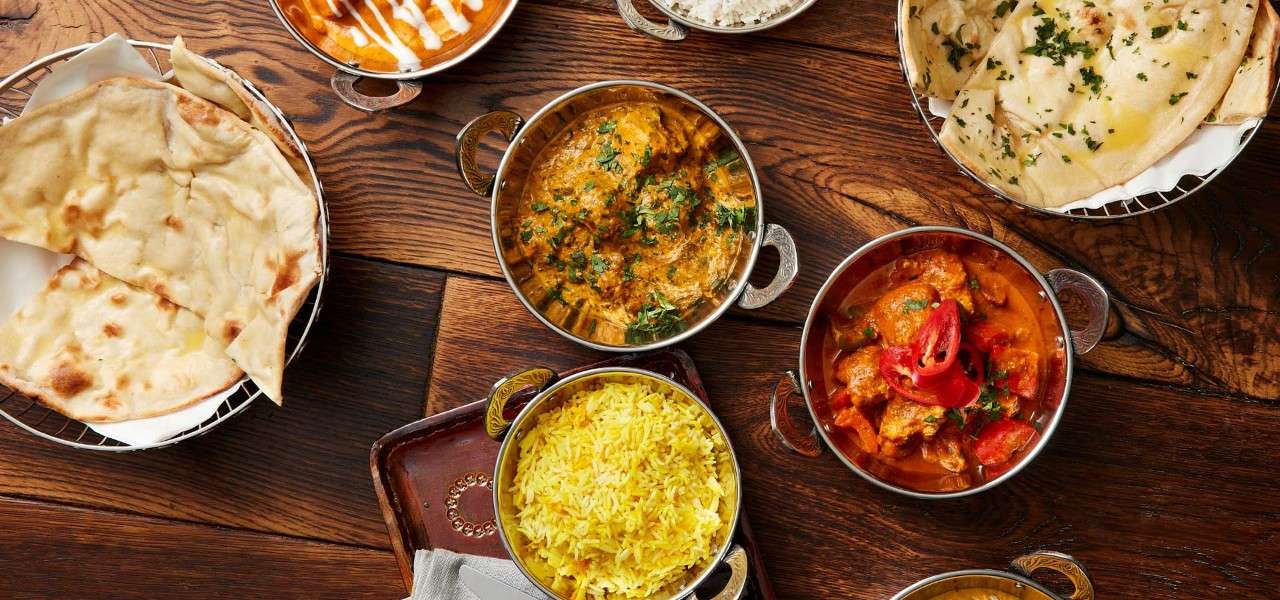 A selection of Indian dishes including, rice, naan bread and a variety of curries.
