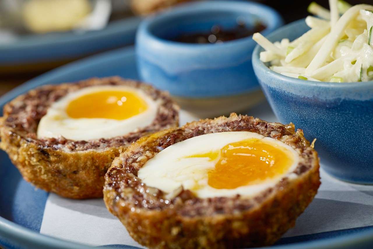 A scotch egg cut in half with a gooey centre.