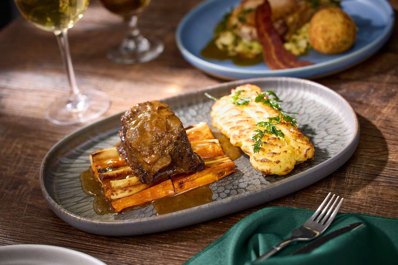Meat dish served on a bed of carrots, drizzled in gravy. 