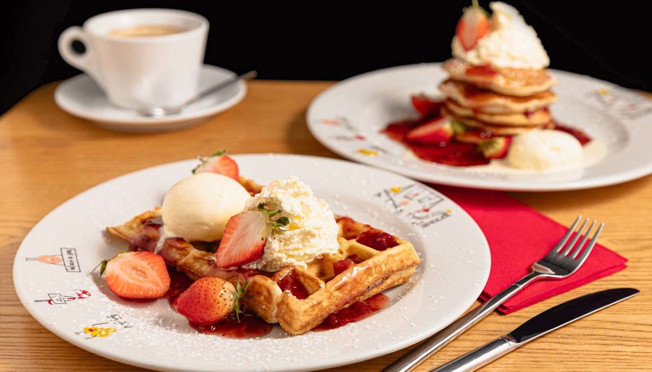 Waffle topped with strawberries and ice cream.