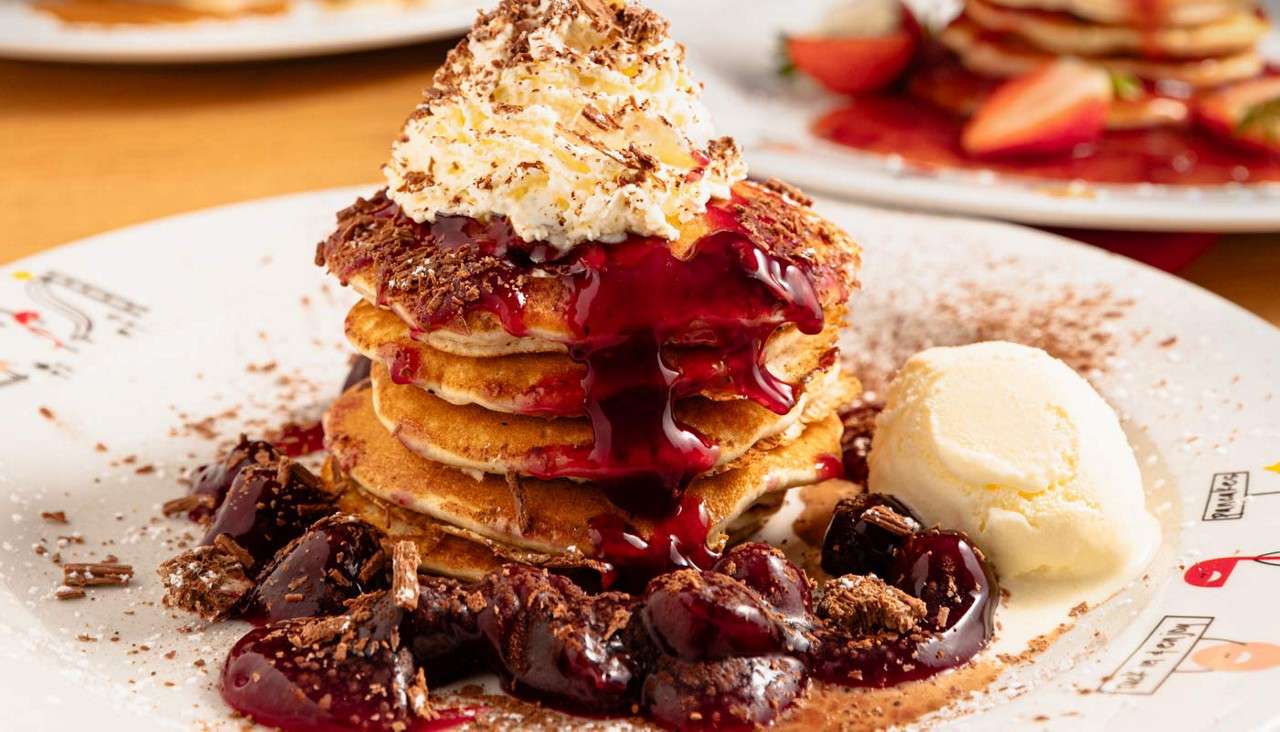 Stacked pancakes topped with whipped cream.